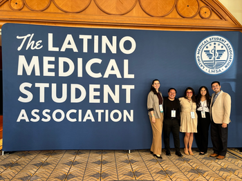 Group of smiling people in front of a sign