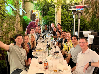 group of people posing for a photo at a long dinner table