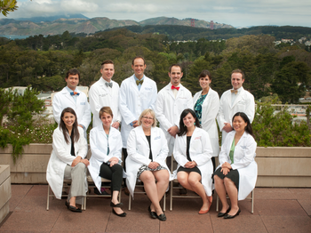 Group of graduates in their white coats posing for a graduation photo