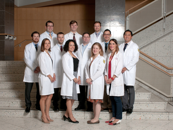 Group of graduates in their white coats posing on stairs