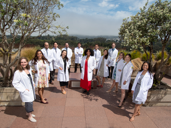 Graduate class of 2020 posing for a group photo in their white coats