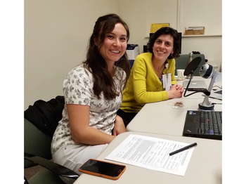 two ladies sitting at a table looking at a computer