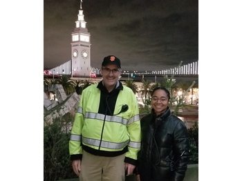 two people posing for a photo in front of a tall building