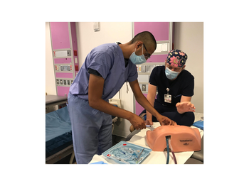 two people in scrubs practicing on a medical simulation dummy