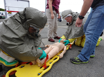 Two people practicing on a dummy on a spinal board