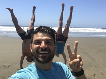 One person close to the camera with two people in the distance doing handstands